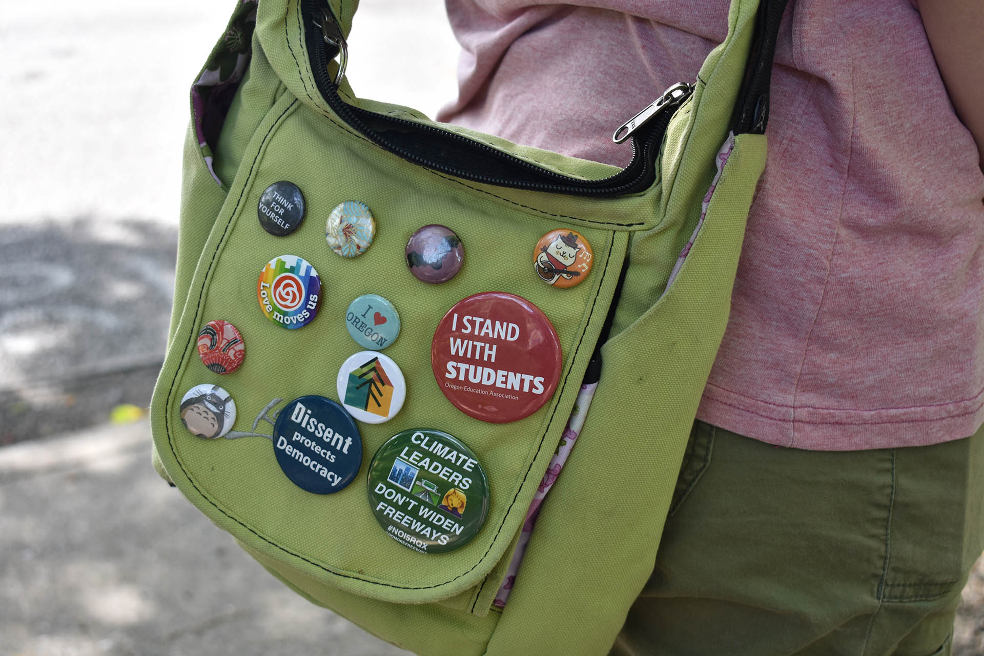 A green bag is scattered with buttons, mostly related to climate action and student movements, but some also feature animated characters like “My Neighbor Totoro.”