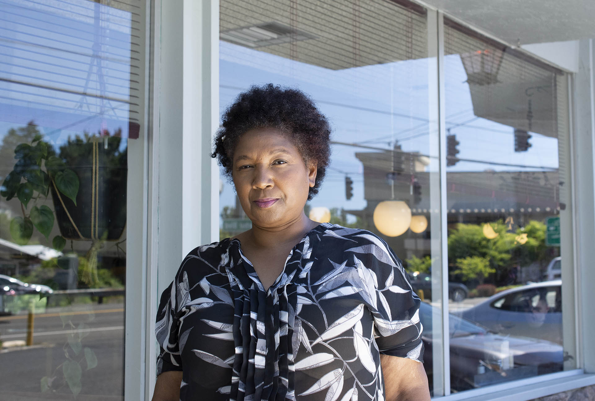 A Black female farmer stands in front of a diner window.