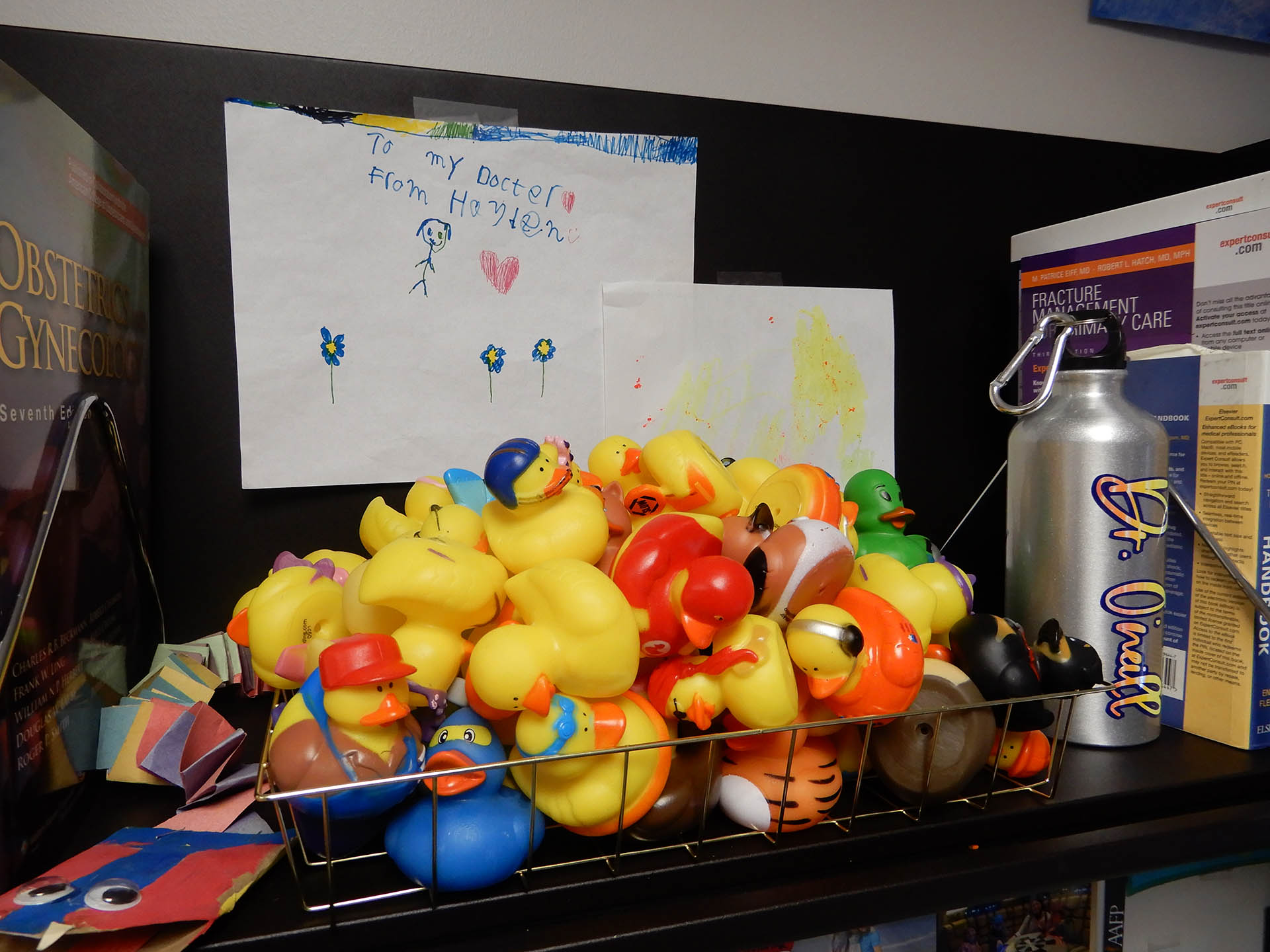 A large, wire tray of rubber ducks sits on a desk.